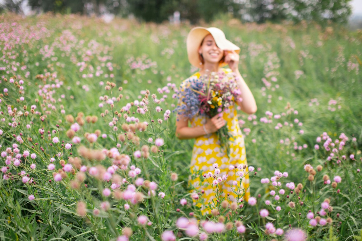 A traveler in a sun hat gathering wildflowers in a blooming meadow